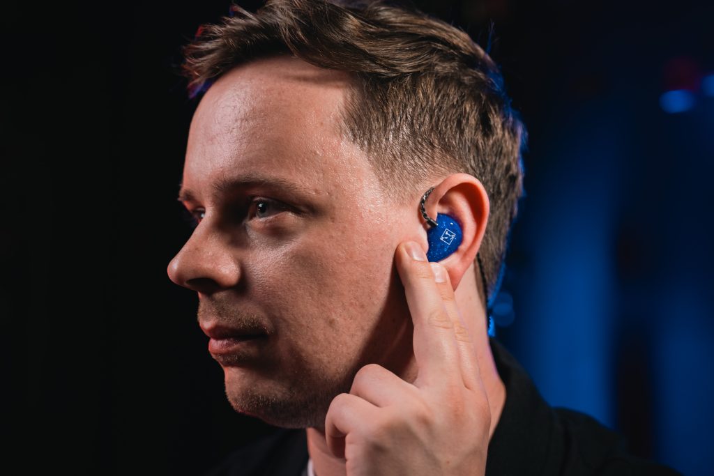 Musiker trägt blaue Hörluchs In-Ear-Kopfhörer